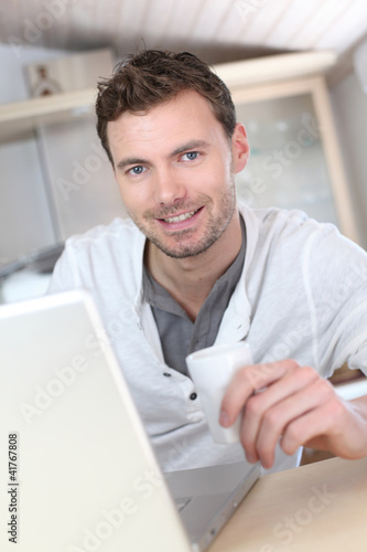 Foto: Man drinking coffee in front of laptop computer Man drinking coffee in front of laptop computer