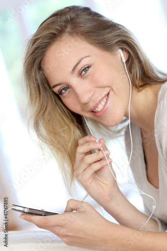 Photo: Cheerful young woman using handsfree device on mobile phone Cheerful young woman using handsfree device on mobile phone