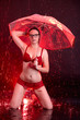 Junge Frau steht im Regen mit Regenschirm