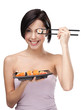 Smiling young female holding sushi with a chopsticks