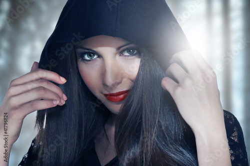 Photo: Portrait of a young woman in hood over forest backgroung Portrait of a young woman in hood over forest backgroung