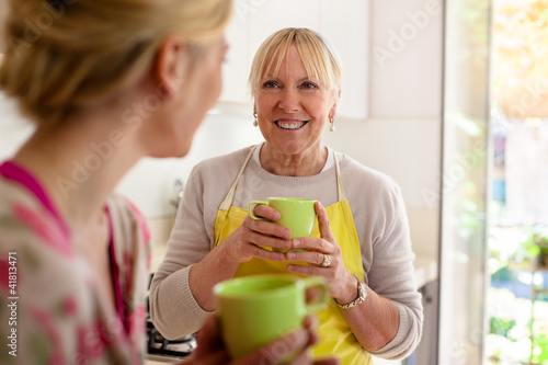 Photo: Mother and daughter talking, drinking coffee in kitchen Mother and daughter talking, drinking coffee in kitchen
