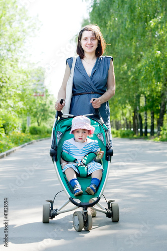 Photo: woman with stroller at summer park woman with stroller at summer park