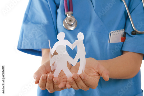 Photo: A female doctor holding paper people, focus on the hands A female doctor holding paper people, focus on the hands