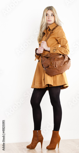 Photo: standing woman wearing coat and fashionable brown shoes with a h standing woman wearing coat and fashionable brown shoes with a h