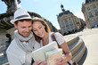 Couple standing by the Place de la Bourse with electronic tablet