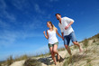Couple having fun runnning down sand dune