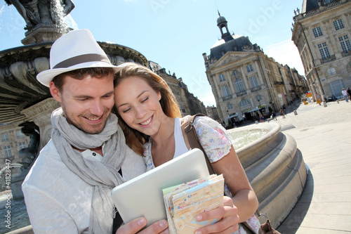 Photo: Couple standing by the Place de la Bourse with electronic tablet Couple standing by the Place de la Bourse with electronic tablet