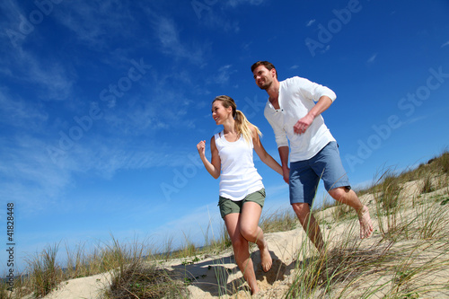 Photo: Couple having fun runnning down sand dune Couple having fun runnning down sand dune