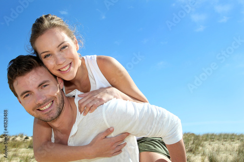 Photo: Man giving piggyback ride to girlfriend on a sand dune Man giving piggyback ride to girlfriend on a sand dune