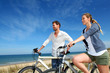 Couple standing on a sand dune with bicycles