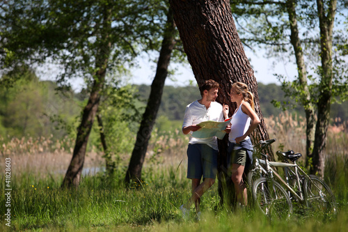 Photo: Couple on a bike ride making a stop to look at map Couple on a bike ride making a stop to look at map