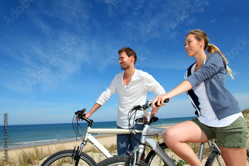 Foto: Couple standing on a sand dune with bicycles Couple standing on a sand dune with bicycles