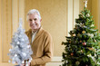 Photo: Senior man by Christmas tree with ornamental tree, smiling, portrait Senior man by Christmas tree with ornamental tree, smiling, portrait