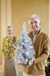 Photo: Senior couple with ornamental Christmas trees, smiling, portrait, close-up of man Senior couple with ornamental Christmas trees, smiling, portrait, close-up of man