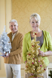Photo: Senior couple with ornamental Christmas trees, smiling, portrait, close-up of woman Senior couple with ornamental Christmas trees, smiling, portrait, close-up of woman