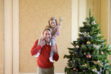 Photo: Girl (4-6) with angel decoration on father's shoulders by Christmas tree, smiling, portrait Girl (4-6) with angel decoration on father's shoulders by Christmas tree, smiling, portrait