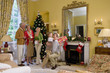Family with presents by Christmas tree, boy (9-11) reaching for gift box