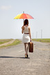 Young fashion girl with umbrella and suitcase at spring outdoor.