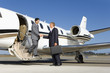Businessman boarding aeroplane on runway, shaking hands with colleague