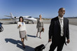 Photo: Businessman with luggage by businesswomen on runway by aeroplane, smiling, elevated view Businessman with luggage by businesswomen on runway by aeroplane, smiling, elevated view