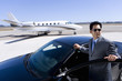 Foto: Businessman in sunglasses by open door of car on runway by aeroplane, elevated view Businessman in sunglasses by open door of car on runway by aeroplane, elevated view