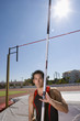 Photo: Young male pole vault athlete with pole by bar, portrait (sun flare) Young male pole vault athlete with pole by bar, portrait (sun flare)