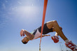 Photo : Young male athlete jumping over bar, low angle view (lens flare) Young male athlete jumping over bar, low angle view (lens flare)