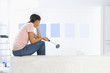 Woman sitting on sofa and examining blue paint samples on living room wall