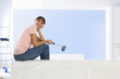 Smiling woman with paint roller sitting on living room sofa