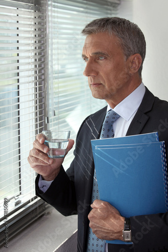 Foto: Businessman looking through his office window Businessman looking through his office window