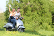 young happy couple on motorbike / scooter on natural background