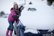 Woman scraping winter snow from car