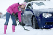 Woman shoveling snow from around car in snowfall