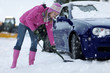 Woman shoveling snow from around car in snowfall
