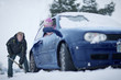 Woman in car watching man shoveling snow from around car