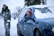 Playful man throwing snow at girlfriend sitting in car