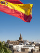 Spanish flag fluttering with cathedral in background, Seville, Spain