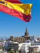 Spanish flag fluttering with cathedral in background, Seville, Spain