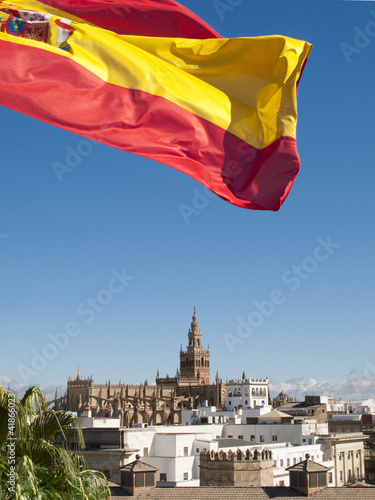 Photo: Spanish flag fluttering with cathedral in background, Seville, Spain Spanish flag fluttering with cathedral in background, Seville, Spain