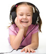 Photo: Cute little girl enjoying music using headphones Cute little girl enjoying music using headphones