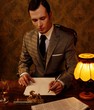 Retro man in grey suit holding a pen