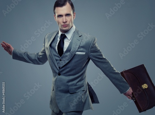 Foto: Businessman with a briefcase isolated on grey Businessman with a briefcase isolated on grey
