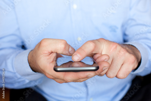 Photo: Close up view of a businessman using a smartphone Close up view of a businessman using a smartphone