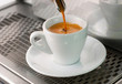 Espresso pours out of a group head into a coffee shot glass.