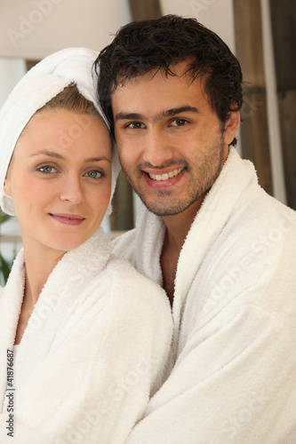 Photo: portrait of young couple all smiles wearing bathrobe portrait of young couple all smiles wearing bathrobe