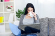 Woman drinking coffee while using laptop Woman drinking coffee while using laptop