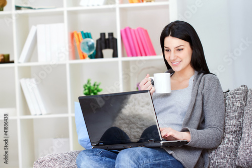 Photo: smiling woman with laptop drinking coffee smiling woman with laptop drinking coffee