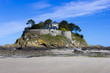 Landscape, seascape with beach and a house on top of a rock.