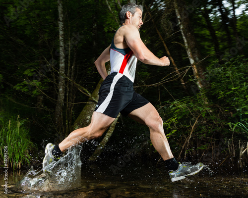 Foto: Jogger durchquert einen Bach Jogger durchquert einen Bach